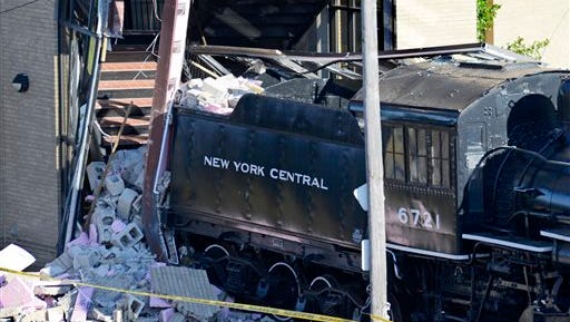 A stationery historic steam engine stands amongst debris after a runaway rail car struck it and caused the locomotive to severely damage a pedestrian bridge support at Union Station, Tuesday, July, 21, 2015, in Utica, N.Y. (Tina Russell/Observer-Dispatch via AP)  ROME OUT; MANDATORY CREDIT
