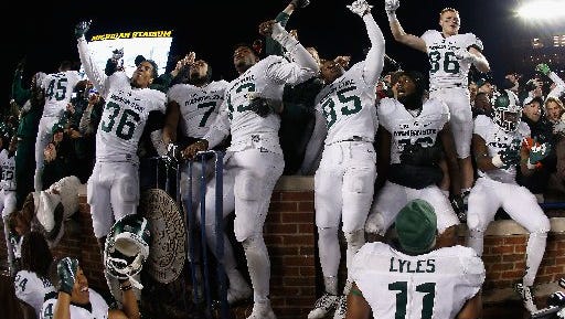 The Spartans celebrate their unlikely win Saturday at Michigan, which kept them in the mix for the College Football Playoff.