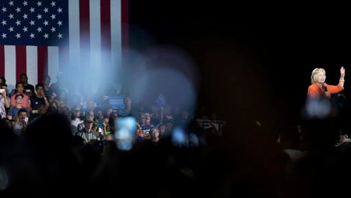In this Aug. 8, 2016, photo, Seddique Mateen, the father of Omar Mateen, the Orlando gay nightclub shooter, far left at bottom, take a photograph with his phone as Democratic presidential candidate Hillary Clinton, right, speaks at a rally at Osceola Heritage Park, in Kissimmee, Fla., Monday, Aug. 8, 2016. (AP Photo/Andrew Harnik)