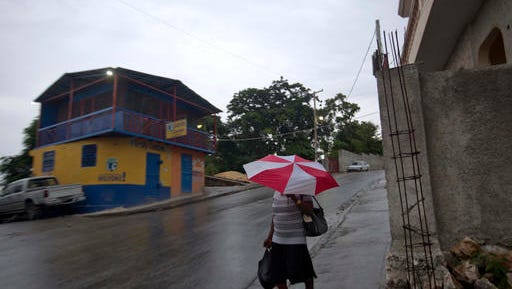 A woman walks with an umbrella as protection from a light rain, in Port-au-Prince, Haiti, Monday. Major Hurricane Matthew is slowly churning northward across the Caribbean and meteorologists say the powerful storm is expected to approach Jamaica and southwest Haiti by Monday night.