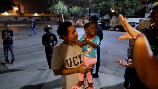 FILE - In this Nov. 14, 2016 file photo, Guatamalan Elvin Vazquez, center, holds a Haitian girl migrating with her family, at a migrant shelter in Tijuana, Mexico. A surge in border crossings and a lack of immigration jail space have prompted the federal government to start releasing Haitian immigrants who have been entering the country in large numbers in recent months, backtracking on a pledge to jail the migrants. A U.S. government official said the decision to free Haitians arriving in Arizona and California is in response to a lack of jail space. Thousands of Haitians have arrived at the U.S. border with Mexico in recent months, many after traveling 7,000 miles by foot, taxi and bus.