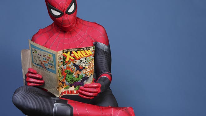 Evan Nuzum, dressed as Spider-Man, of Escondido, Calif., reads a comic book as he poses for a portrait on day one of last year's Comic-Con International in San Diego. This year, Comic-Con took place virtually online.