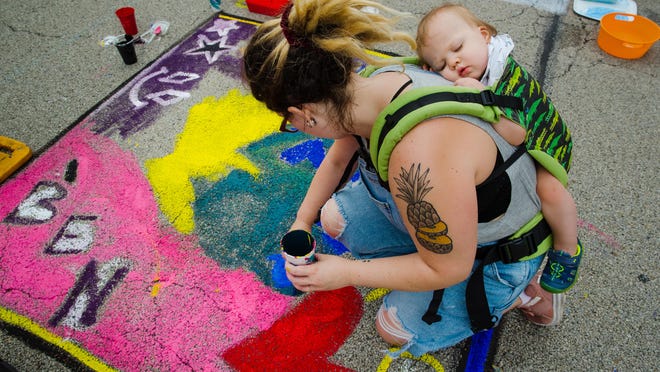 Rachel Morrison's 1-year-old son Benjamin sleeps while nestled in a carrier on her back during the Springfield Art Association's 2019 Paint the Street event in downtown Springfield on June 22, 2019. Morrison said painting was much harder while carrying her 20-pound son.