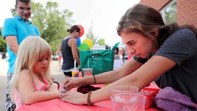 Shane Al-Ghetta watches as his daughter Leyla Al-Ghetta, 4, gets a temporary tattoo from Nora Martin during a community block party at Wilson Elementary School Tuesday, Aug. 30, 2016, in Neenah, Wis. Danny Damiani/USA TODAY NETWORK-Wisconsin