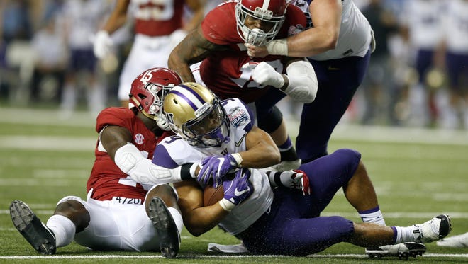 Washington running back Myles Gaskin is brought down by Alabama defensive back Ronnie Harrison during the second quarter of the Peach Bowl.