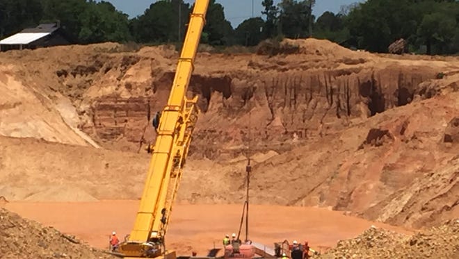 In this photo released by the Mississippi Emergency Management Agency, a new crane is used Tuesday to assist in the recovery efforts to remove two workers buried under a landslide at the bottom of a pit at Green Brothers Gravel Co., in Crystal Springs.