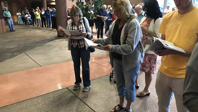 Voters read information pamphlets as they wait in line at a polling station Tuesday at the Dixie Convention Center in St. George.