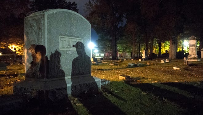 Ghost tour attendees cast shadows on gravestones as they are guided through Polk Cemetery on Saturday, Oct. 28, 2017, during Epic Haunted Tours' "History, Legends & Maybe Some Ghosts Tour" in Bolivar.