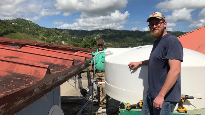 John-Mark Woodard, front, and Russell Weathersby help install a water purification system on a rooftop in Puerto Rico.