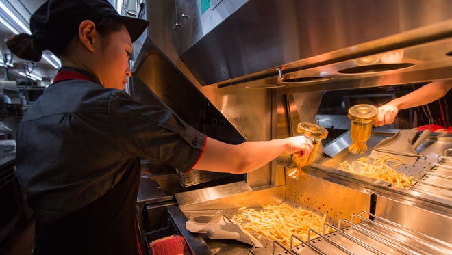 A McDonald's worker sprinkles salt on french fries.