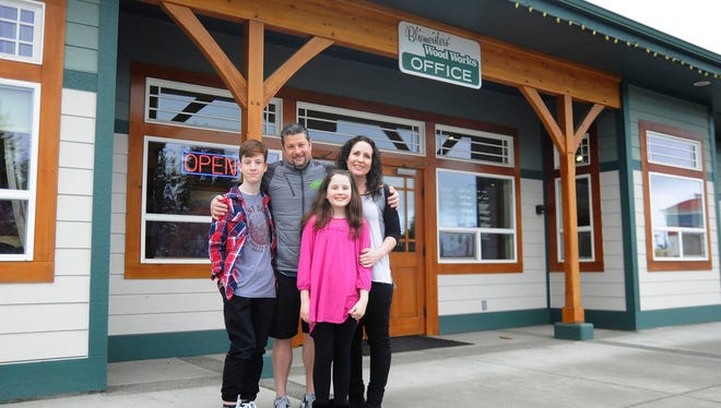 In this March 30, 2018, photo, Jason Doig, his wife Jeni and children Ethan 10, and Rylie, 10, stand outside Doig's business, Bliemeisters' Wood Works in Carlsborg, Wash. Doig was awarded the Carnegie Medal for heroism after risking his life preventing a woman from jumping off the Hood Canal Bridge in March 2017. (Jesse Major/The Peninsula Daily News via AP)