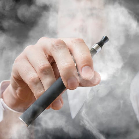 Man holding a vaping device with smoke surrounding