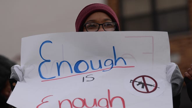 Rahma Mfinanga, a junior at Clarenceville High School, holds a sign along Middlebelt Road during a 17-minute walkout beginning at 10 a.m. Wednesday, March 14, 2018 to support a nationwide walkout to urge changes making schools safer from gun violence.