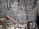 A bed frame stands amid charred remains of a Redding