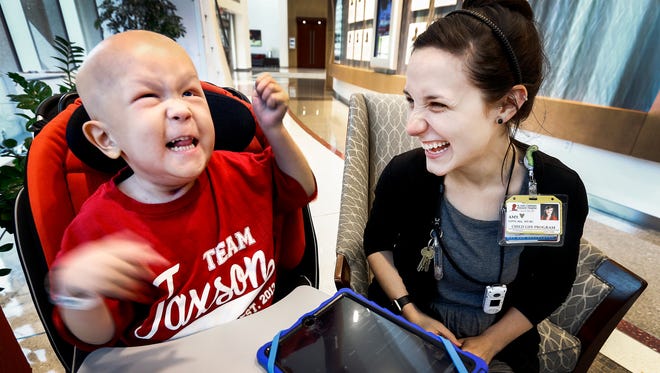 St. Jude Children's Research Hospital music therapist Amy Love (right) plays music on her iPad with patient Jaxson Harper, 3, who suffers from Rhabdomyosarcoma during a session at the hospital Thursday afternoon. Hospital patients who may need more than medical treatment for their life-threatening illnesses also benefit from the music therapy offered by Love, who sings, plays instruments and does other performances. 