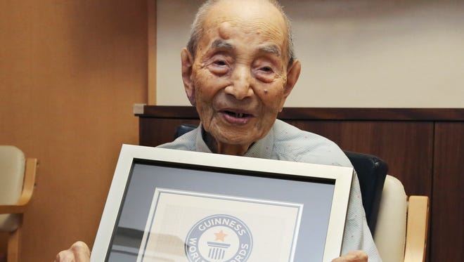 In this Aug. 21, 2015, file photo, Yasutaro Koide, 112, holds the Guinness World Records certificate as he is formally recognized as the world's oldest man at a nursing home in Nagoya, central Japan. Koide, who was born on March 13, 1903, died on Tuesday, two months short of his 113th birthday.