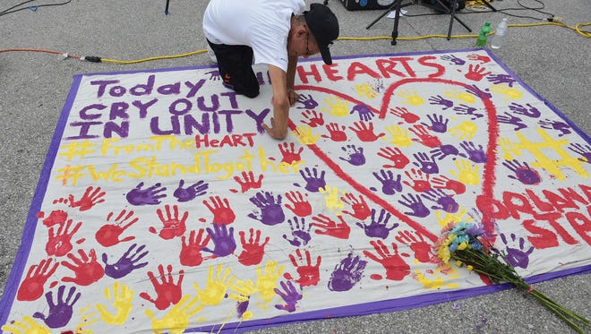 A man places a hand print on a makeshift memorial in a parking lot near the Pulse nightclub in Orlando, Florida on June 12, 2016.