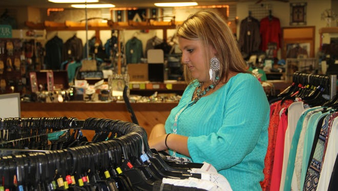 Dollar Boots & Jeans Manager Shawna McNatt restocks clothes racks at the family owned store.