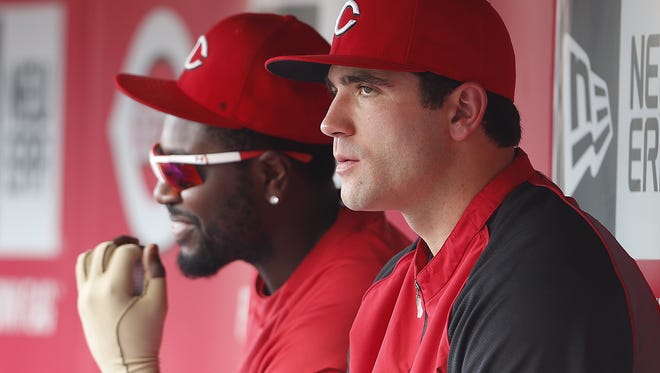 Cincinnati Reds first baseman Joey Votto (19), left, and second baseman Brandon Phillips (4), chat with one another in the dugout.