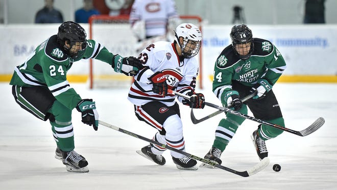 St. Cloud State's Robby Jackson (23) tries to get past Christian Wolanin (24) and Austin Poganski (14) of North Dakota earlier this season at the Herb Brooks National Hockey Center. The Huskies and the Fighting Hawks are separated by one win in the battle for first place in the NCHC.