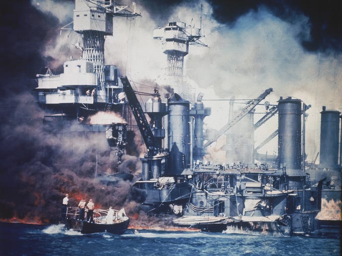 A small boat rescues a USS West Virginia crew member