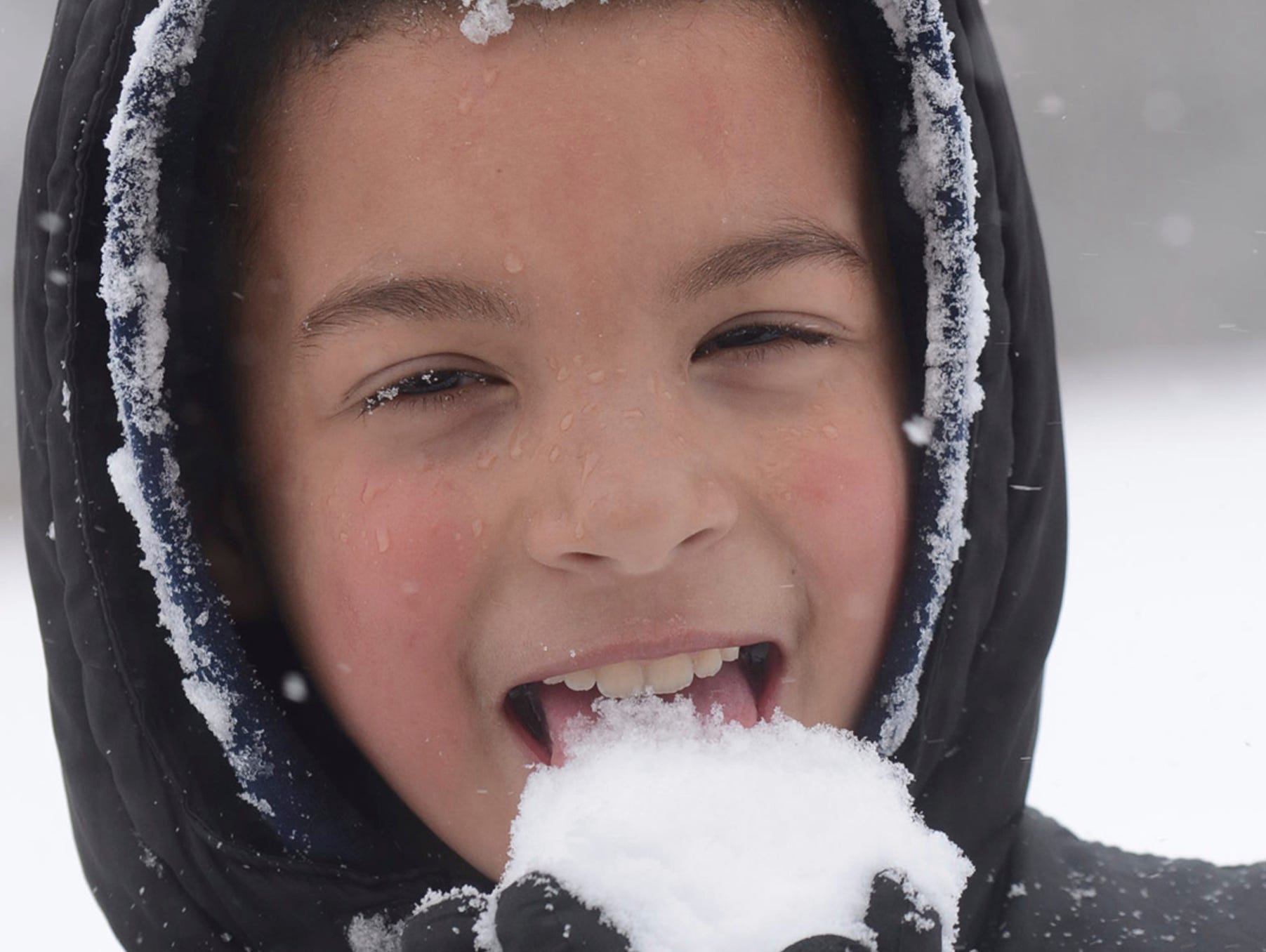 Cristian Severino, 8, enjoys a handful of snow as he takes a break March 10, 2017, from sleigh riding in a field in Hazleton, Pa.
