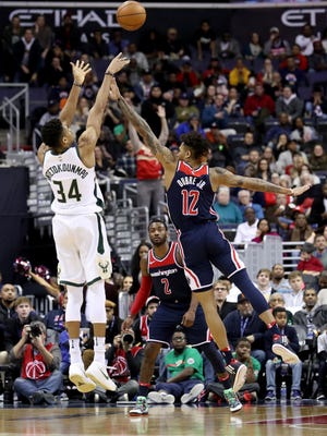 Giannis Antetokounmpo  hits a three-pointer shot over the Wizards' Kelly Oubre Jr.  last week.
