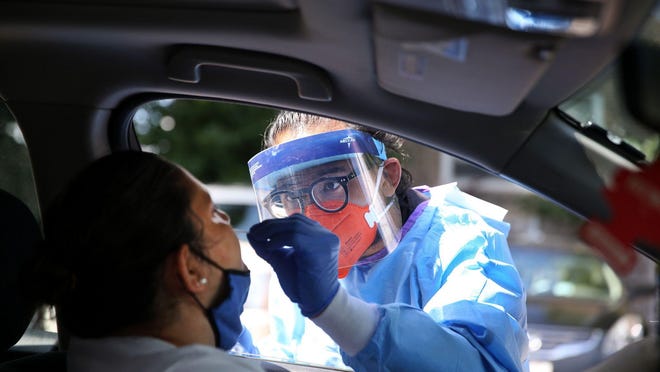 Justin Reyes administers a COVID-19 test to Maria Suarez outside of Heartland Health Center in Chicago's Rogers Park neighborhood on July 10, 2020.