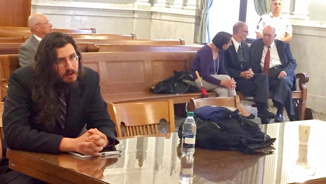 Michael Rotondo, left, sits during an eviction proceeding in Syracuse, N.Y., brought by his parents, Mark and Christina, of Camillus. The two parents confer with their lawyer, Anthony Adorante, in the court gallery behind.
