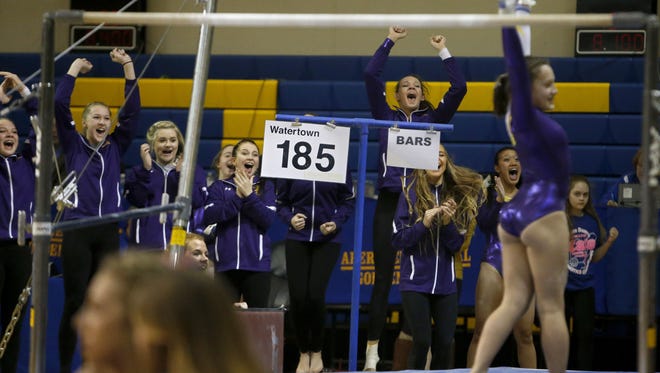 Members of the Watertown gymnastics team cheer as Myah Morris, foreground right, finishes her routine on the bars Friday at the Class AA State Gymnastics Meet in Aberdeen.