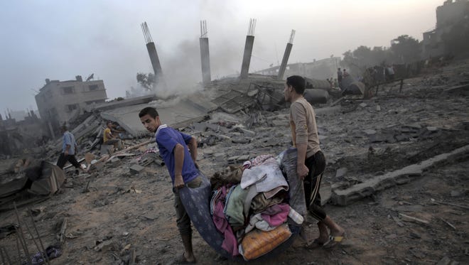 Palestinians try to salvage belongings from a bombed-out house in Gaza, destroyed by an overnight Israeli airstrike.