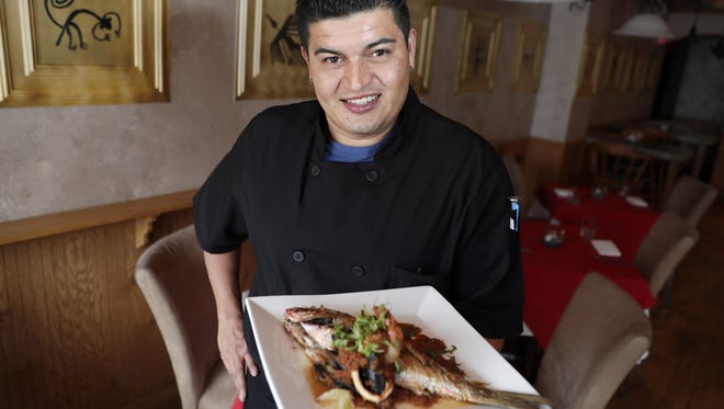 Hugo Torres, co-owner and head chef at Pisco Mar, a new Peruvian restaurant on College Avenue, holds a red snapper with black mussels, calamari and shrimp.