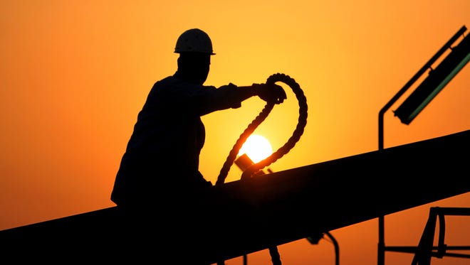In this file photo taken July 7, 2010, an unidentified oilfield worker ties pipes to be raised on an oil rig as the sun sets in the Persian Gulf desert oil field of Sakhir, Bahrain. Exxon earned the majority of its income from exploration and production operations in foreign waters, particularly in Africa, Asia and the Middle East. Exxon's results showed a jump in profits across its exploration and production, refining and chemicals businesses. (AP Photo/Hasan Jamali, file)