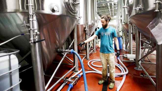 John Helberg walks between fermenters in the cellar at Hi-Wire Brewing in this 2016 photo. Congress is considering cutting taxes for small breweries like Hi-Wire.
