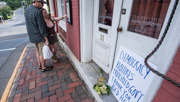 Passersby examine the menu at the Red Hen...
