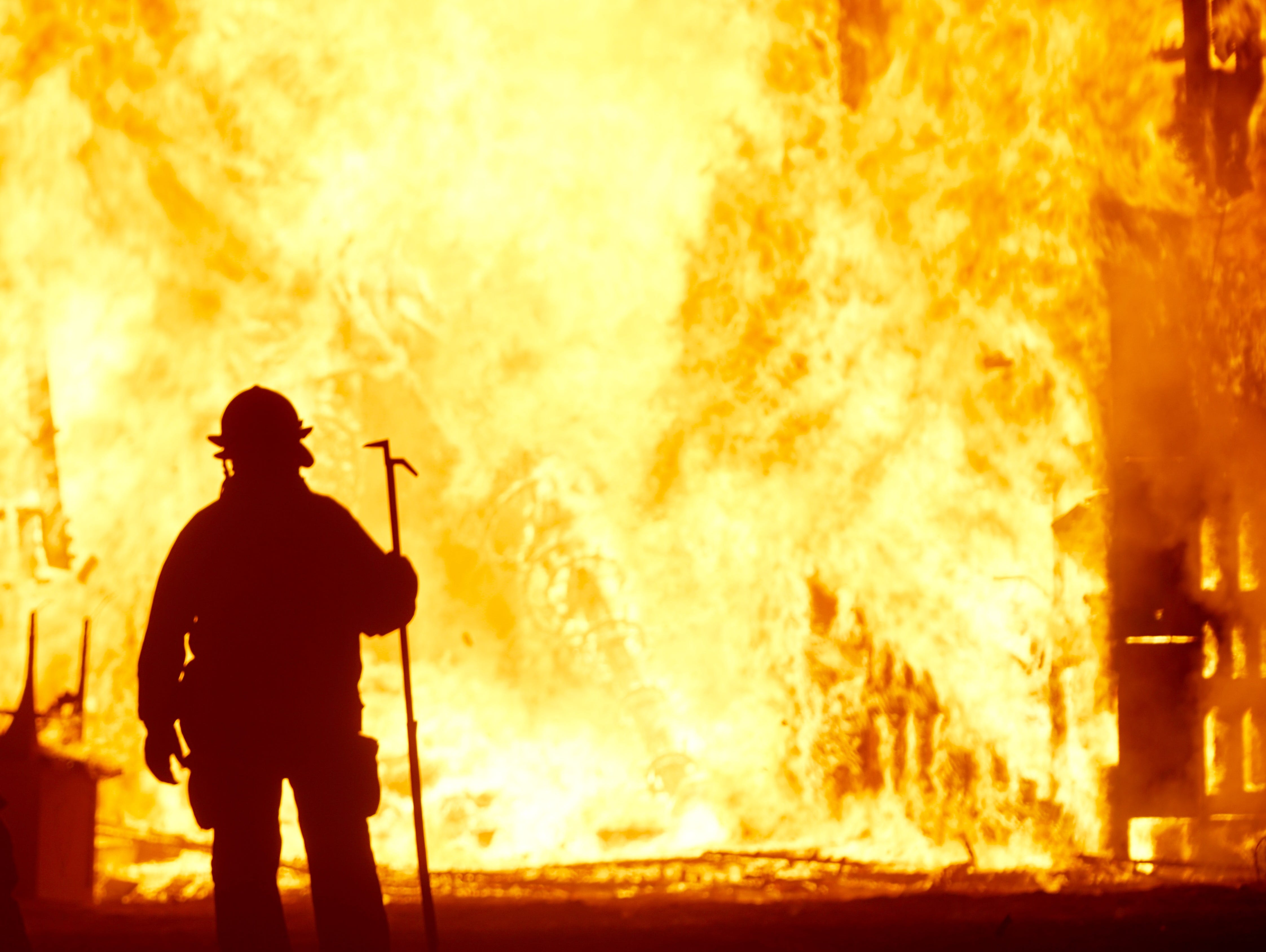 A firefighter, his silhouette obscured by the intense heat waves, watches at the Man burns at Burning Man on Saturday, Sept.2, 2017.
