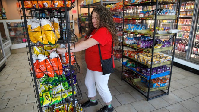 Worker Sarah Coons stocks inventory on the shelves at the Freedom Market, a neighborhood-run corner store.