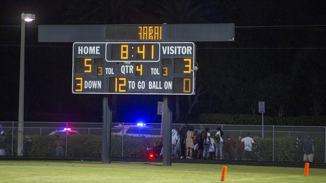 A group gathers around one of the victims of a shooting at Palm Beach Central High School. Two adults were shot on Aug. 17, 2018 at a football game between Palm Beach Central and William T. Dwyer high schools, authorities said. The gunfire sent players and fans screaming and stampeding in panic during the fourth quarter of the game.