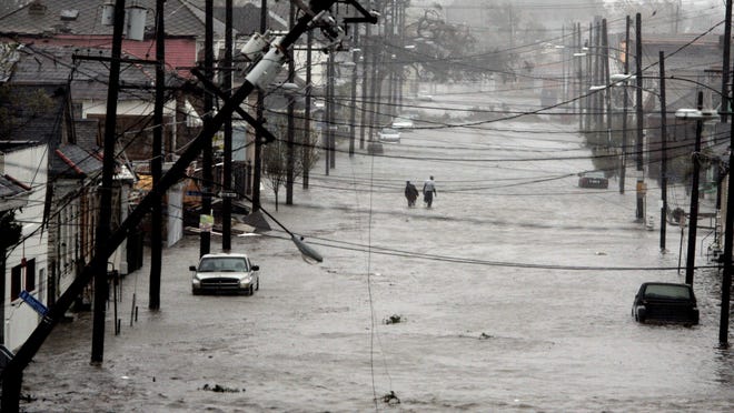 Two people walk down a flooded street as Hurricane Katrina hits New Orleans, causing massive flooding on Aug. 29, 2005. Officials called for a mandatory evacuation of the city, but many residents remained in the city.