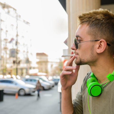 Man with green headphones smoking a cigarette