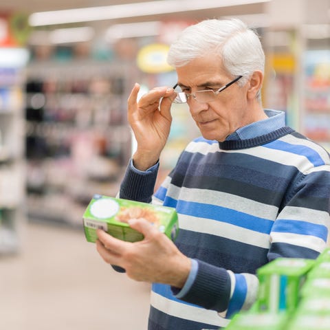 Older man in a supermarket adjusting eyeglasses