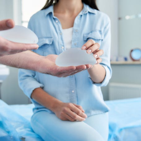 Woman receiving consultation in a clinic while a doctor holds a pair of silicon breast implants.