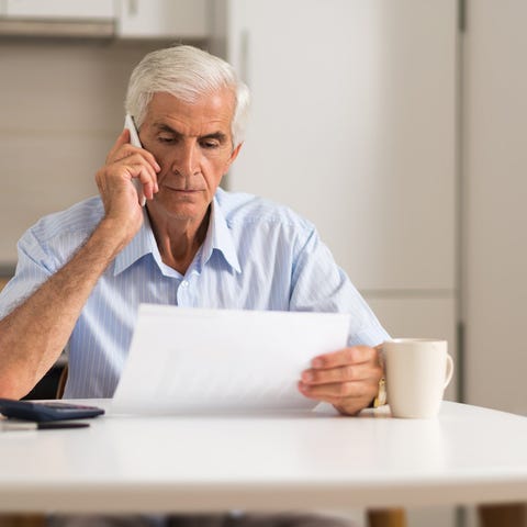 Older man holding phone to ear while looking at do