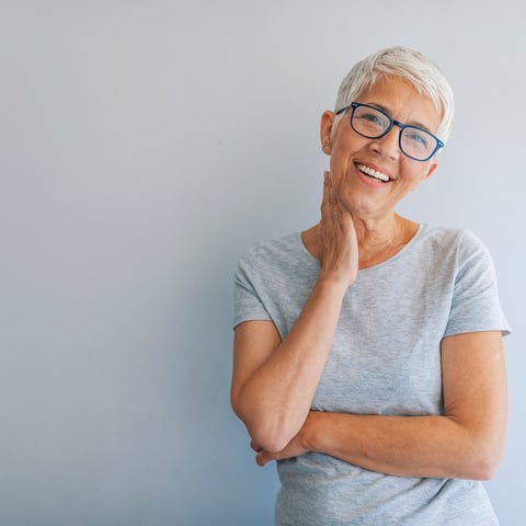 Smiling older woman standing against gray wall