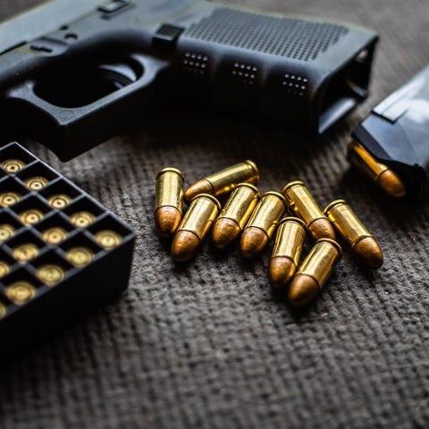 A firearm with bullets on a table.