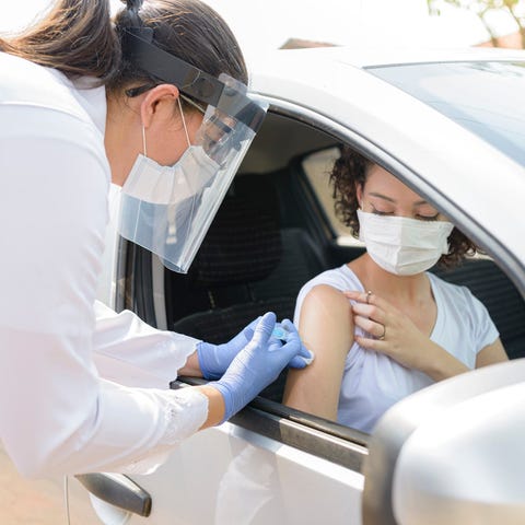 Vaccination shot for woman in passenger seat of ca