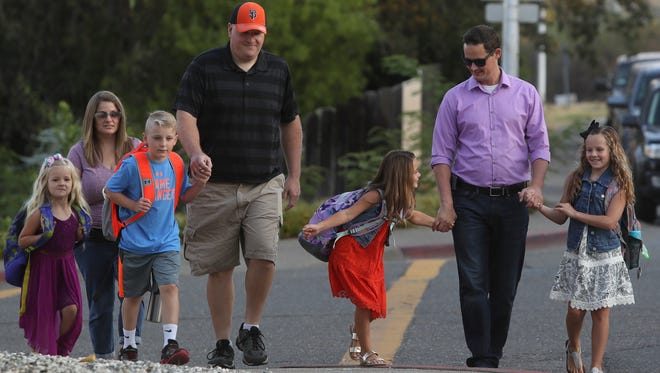 Clint Boots, left, his wife Heather, daughter Chloe, son, Caden, along with Jeremy Caudell, right, and daughters Aubrey and Emory make their way along Manzanita Hills Avenue on Wednesday to start the school year at Manzanita Elementary School in Redding.