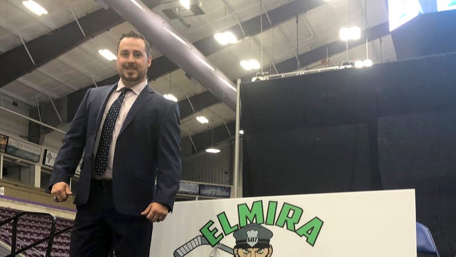 Elmira Enforcers head coach Brent Clarke stands next to the team's logo during a press conference Aug. 2 at First Arena in Elmira.