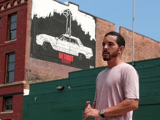 Detroit artist Nic Notion is seen by a mural he painted