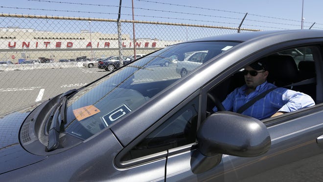 In this July 15, 2015 photo, Uber driver Karim Amrani sits in his car parked near the San Francisco International Airport parking area in San Francisco. Uber says it has settled a pair of major class-action lawsuits in California and Massachusetts that will keep its drivers independent contractors instead of employees. The settlement announced by the ride-hailing company Thursday night, April 21, 2016, is a major step toward keeping its current thriving business model that has been threatened as drivers sought more rights.